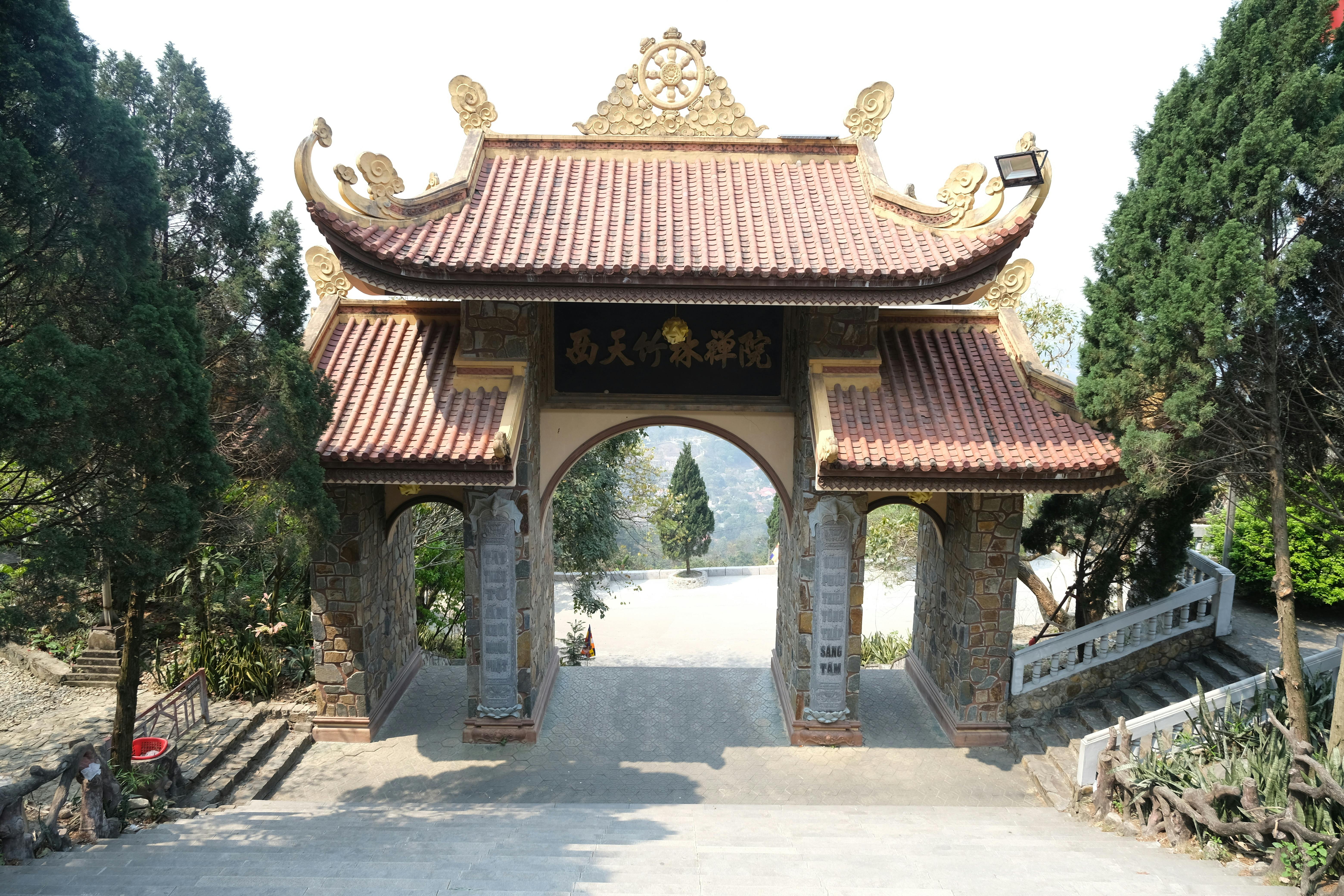 Traditional Buddhist temple gate surrounded by lush greenery and peaceful ambiance.