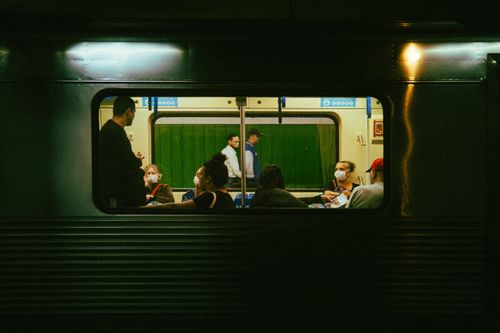 Free A view of passengers inside a train car at night, some wearing masks. Stock Photo