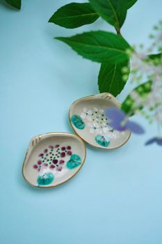 Flat lay of ceramic plates with hydrangea design against a light blue backdrop. — photo by Yohira Ortensia