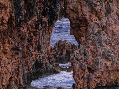 Free Stunning view of ocean waves through a rocky archway, showcasing nature's beauty and power. Stock Photo