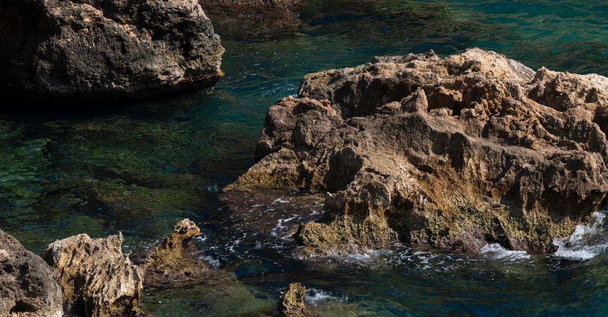 Deep Cliff With Rocks Craggy Coastal Rocks in Deep Blue Ocean Water · Free Stock Photo