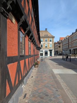 Explore a charming European street featuring iconic half-timbered architecture under a clear blue sky.
