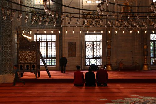 Free People praying inside a beautifully decorated mosque with intricate patterns and lighting. Stock Photo
