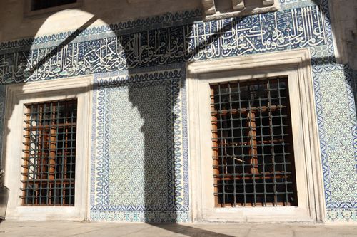Free Beautiful Arabic calligraphy and geometric patterns adorn a mosque wall in bright sunlight. Stock Photo