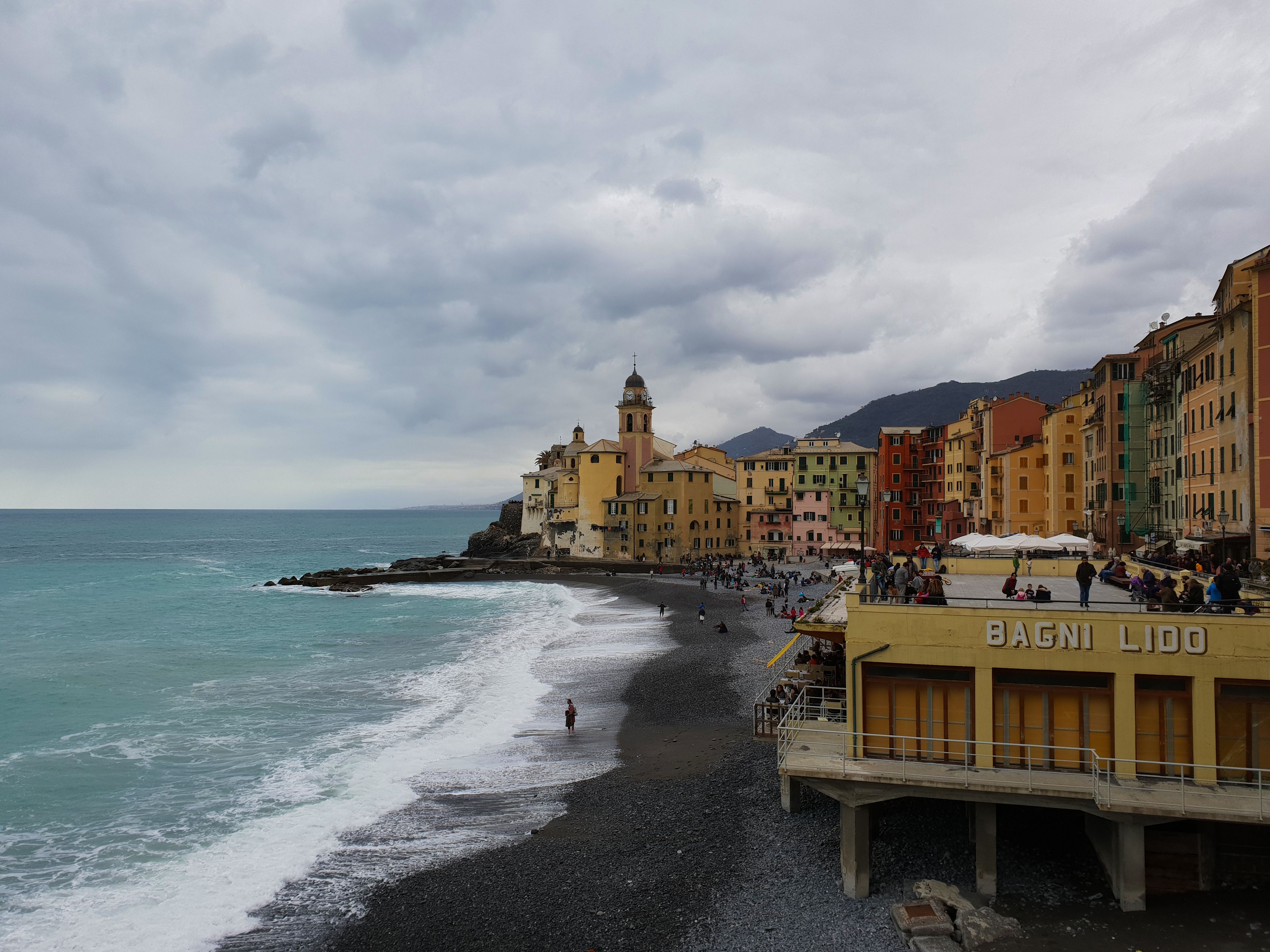 Picturesque coastline of Camogli, Italy with colorful buildings and dramatic clouds.