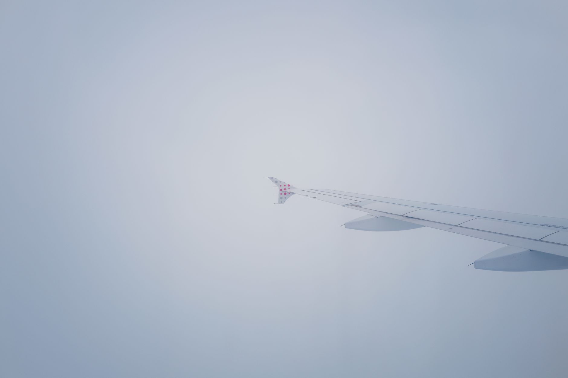 A minimalist ultra-luxury private jet cabin interior featuring a serene window view of clouds at high altitude.
