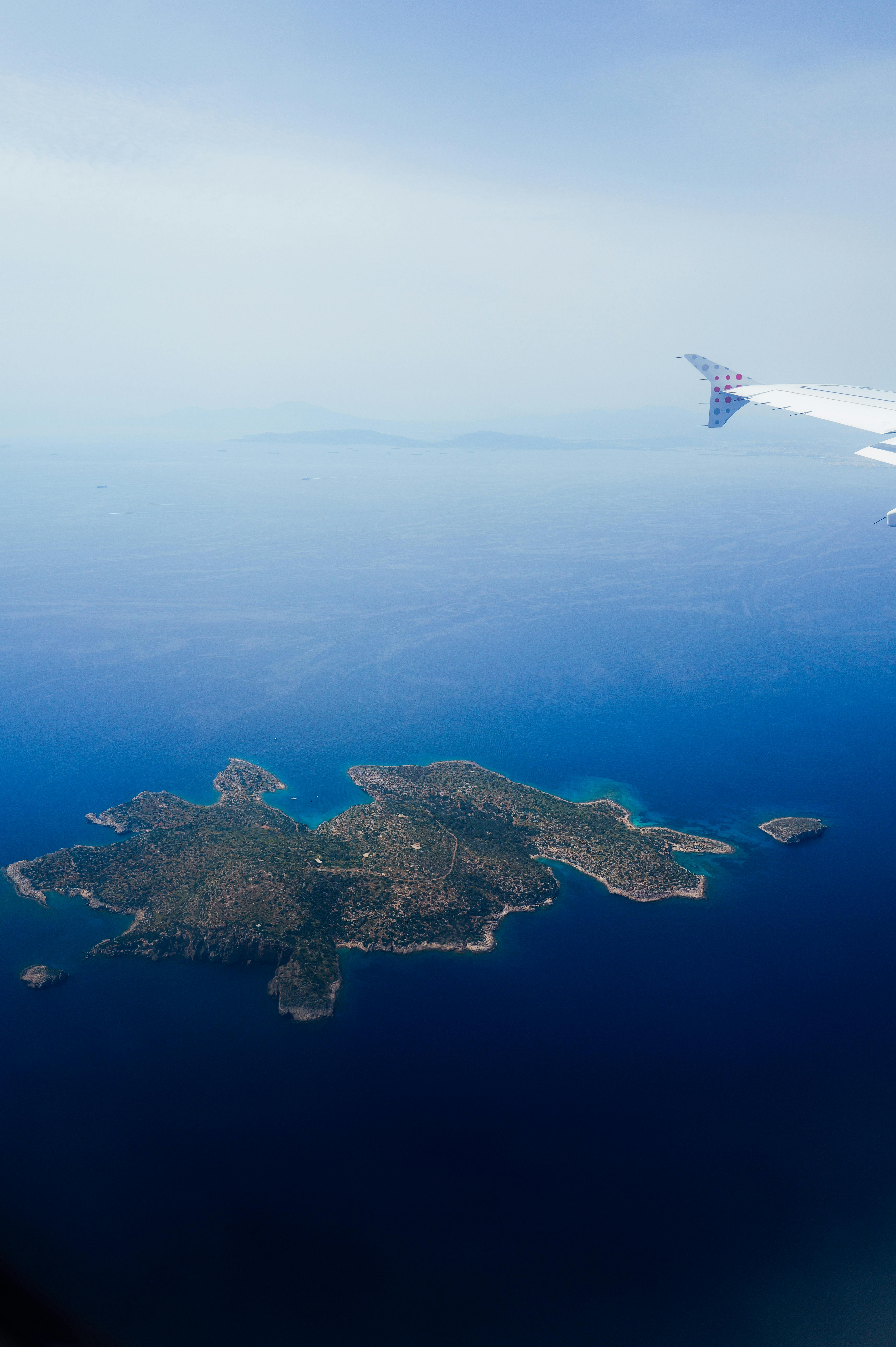 Stunning aerial shot of a secluded island viewed from an airplane window, featuring deep blue ocean waters.