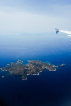 Stunning aerial shot of a secluded island viewed from an airplane window, featuring deep blue ocean waters.