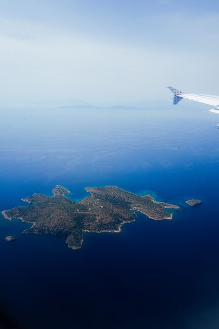 Stunning aerial shot of a secluded island viewed from an airplane window, featuring deep blue ocean waters.
