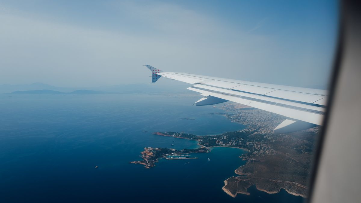 Scenic aerial view from airplane window showcasing coastline and sea, perfect for travel content.