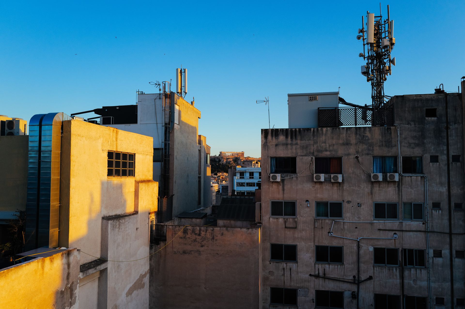 Urban skyline view showcasing rooftops and antennas during daytime with clear blue skies.