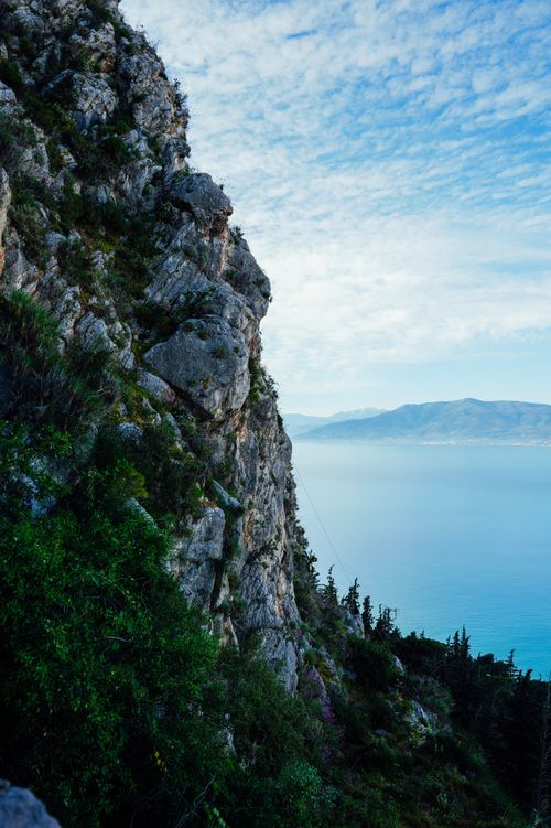 Free Stunning cliff view with lush greenery and a vast ocean backdrop. Stock Photo