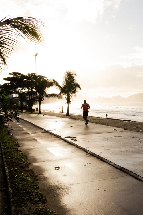 Free A person jogging along the scenic beachfront path in Espírito Santo, Brazil at sunrise. Stock Photo