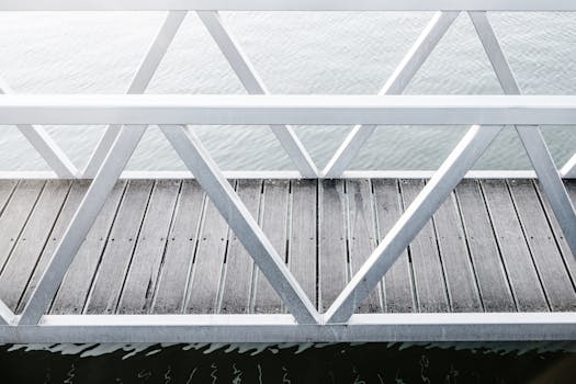 平静水面上，一座木制码头简约而立，金属栏杆映衬其中，尽显设计与建筑灵感之美