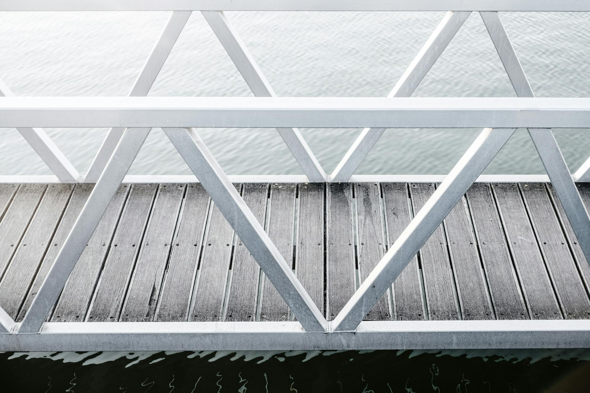 A minimalist view of a wooden dock with metal railings over calm water. Perfect for design and architecture inspiration.