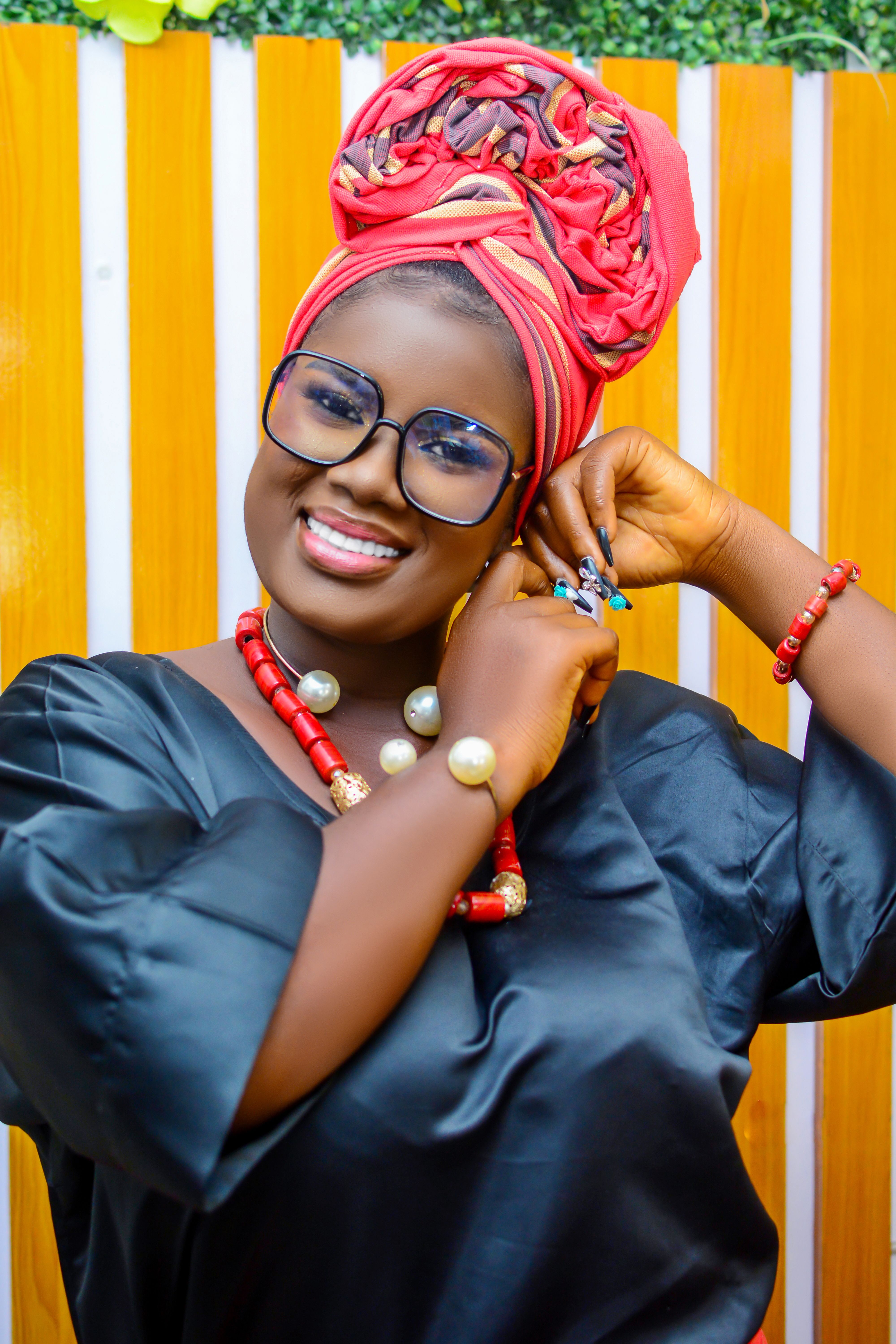 Joyful woman wearing a vibrant headwrap and accessories, exuding confidence and style.