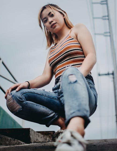 Selective Focus Photo of Woman in Distressed Jeans Squat Posing