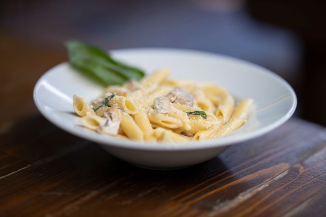 Delicious creamy penne pasta served in a white bowl with garnish, perfect for a cozy meal.