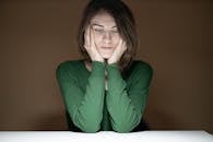 在低光环境中，一位身穿绿色毛衣的体贴女人向下看去