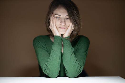 在低光环境中，一位身穿绿色毛衣的体贴女人向下看去