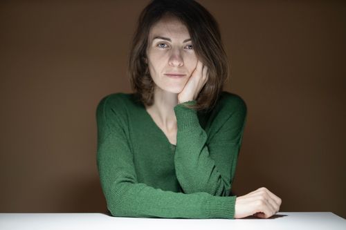 Free A thoughtful woman sitting at a table indoors, captured with soft lighting. Stock Photo