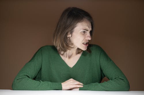 Woman in Green V-neck Sweater Leaning on Table