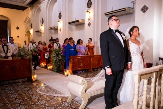Elegant indoor wedding ceremony with bride and groom standing in classic church setting.