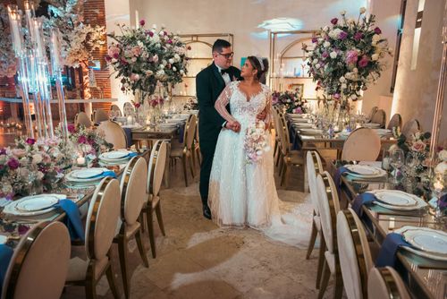 Free A beautifully decorated indoor wedding venue featuring a bride and groom surrounded by elegant floral arrangements. Stock Photo