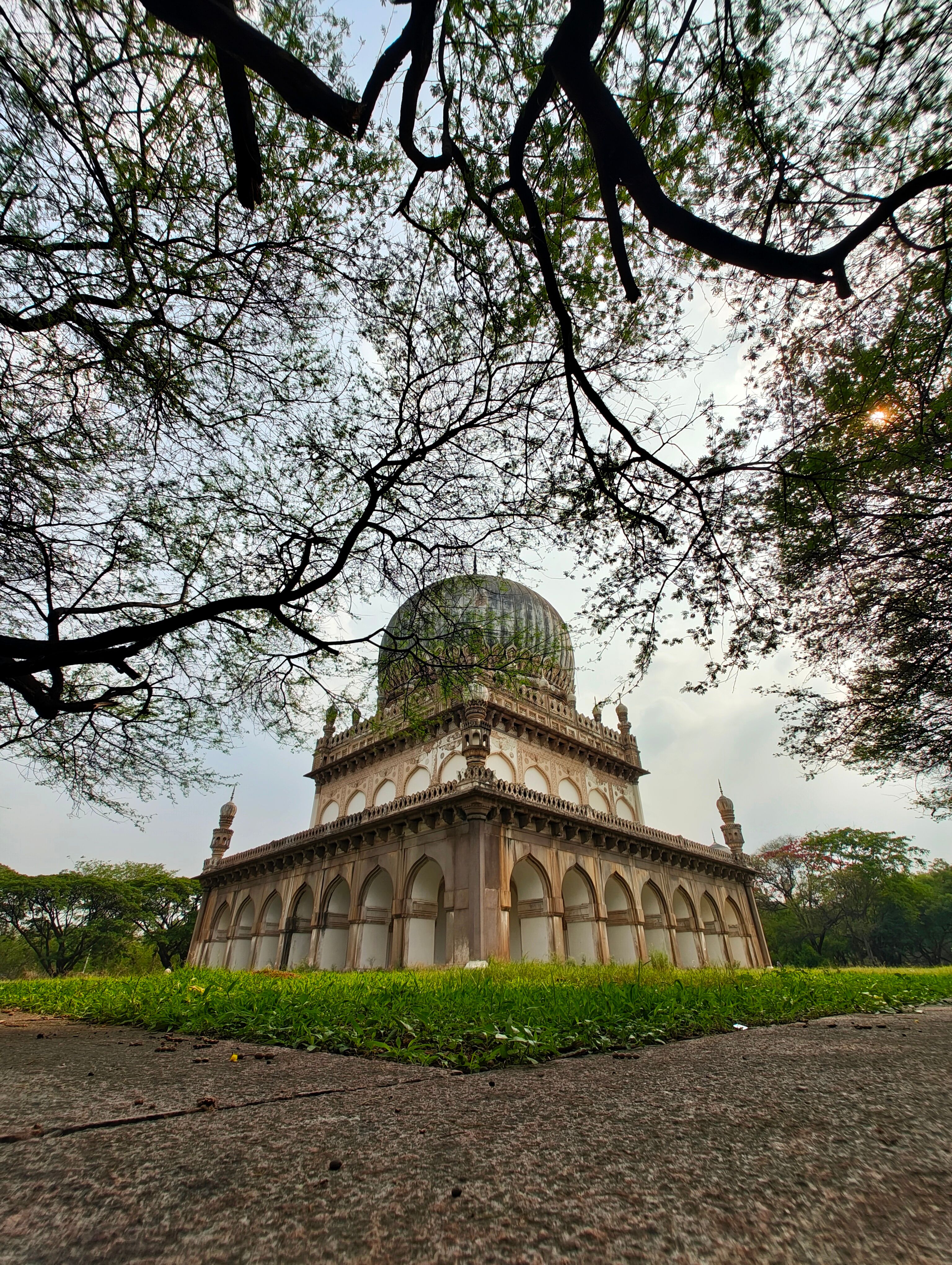 Historic Qutb Shahi tomb under tree canopy in Hyderabad, India.