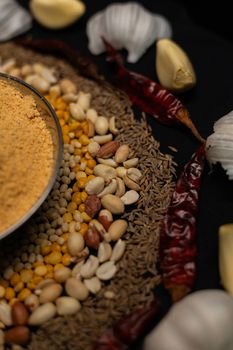 Close-up of Indian spices and lentils arranged with garlic and dried chili peppers.
