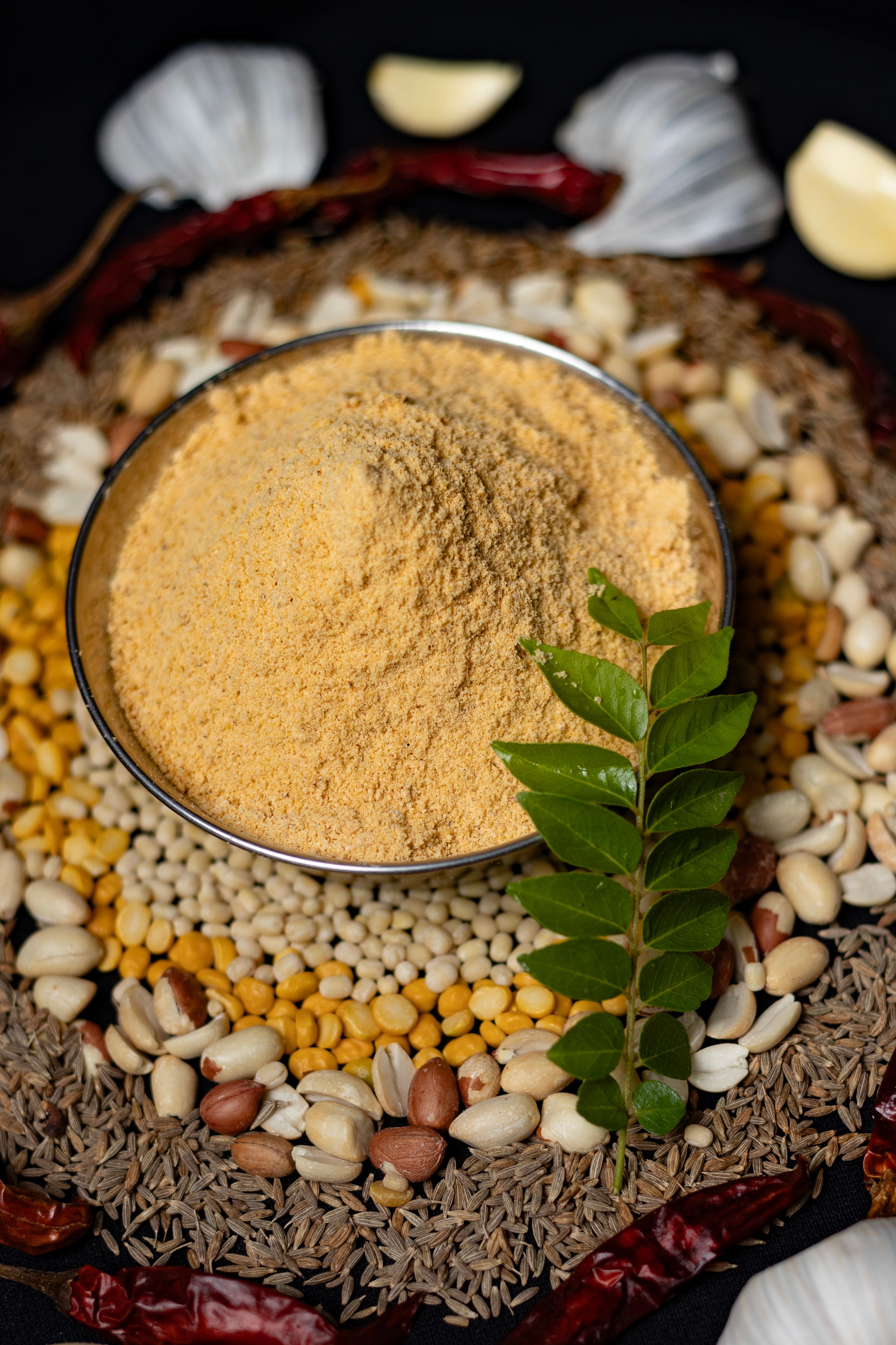 Traditional Indian spice blend surrounded by mixed lentils, nuts, and herbs in Dindigul, Tamil Nadu.