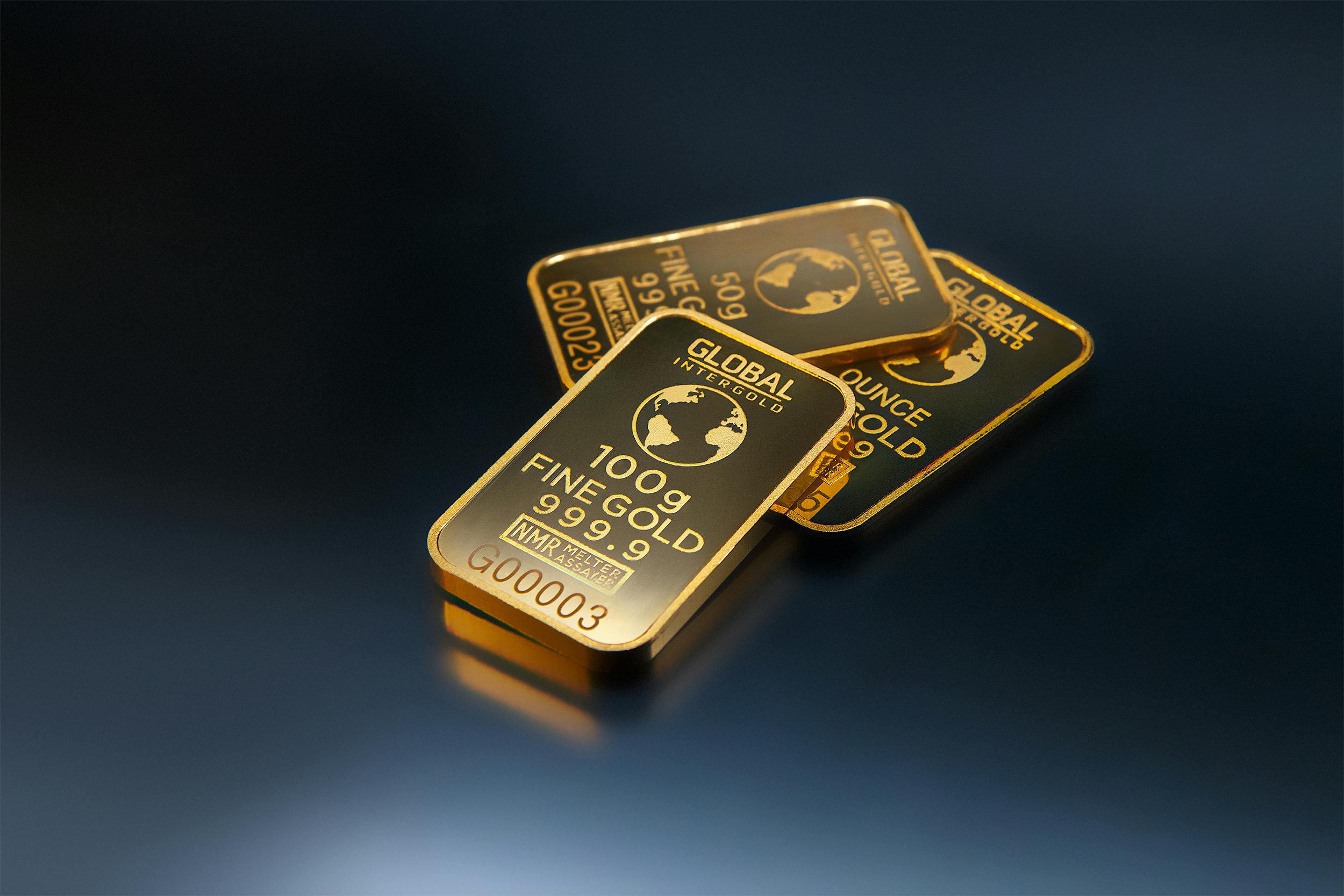 Three Gold Bars Against Dark Background · Free Stock Photo