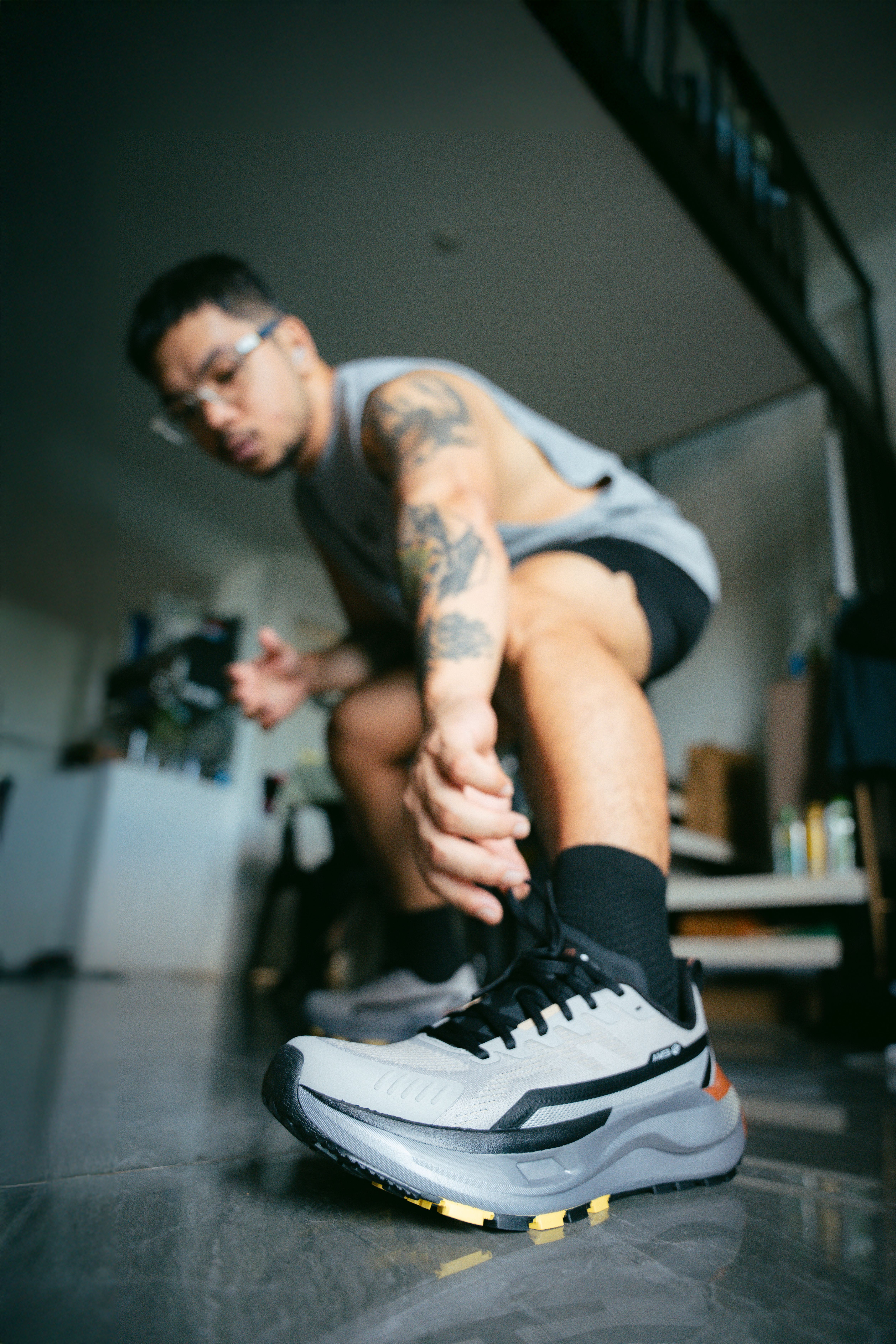 Focused athlete tying running shoes, preparing for workout indoors.