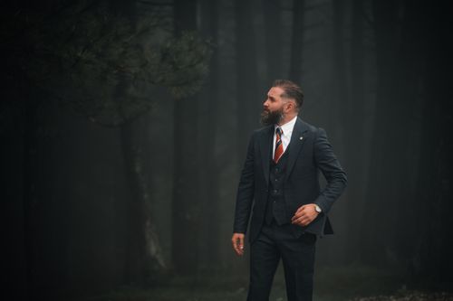Free A man in a suit stands confidently in a misty forest, exuding elegance. Stock Photo