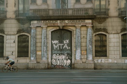 Cyclist in motion in front of historic government building facade with graffiti art.