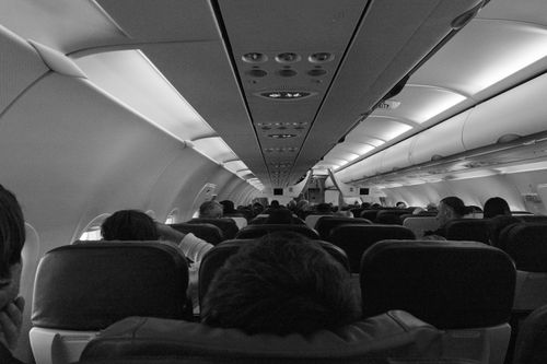 Free Black and white view of passengers seated inside an airplane cabin. Stock Photo