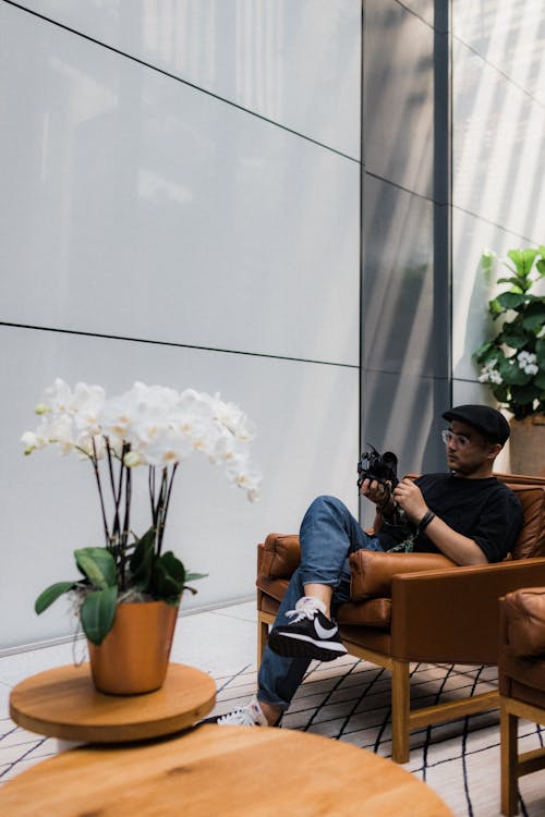 Man Sitting On A Brown Leather Armchair Checking On His Camera