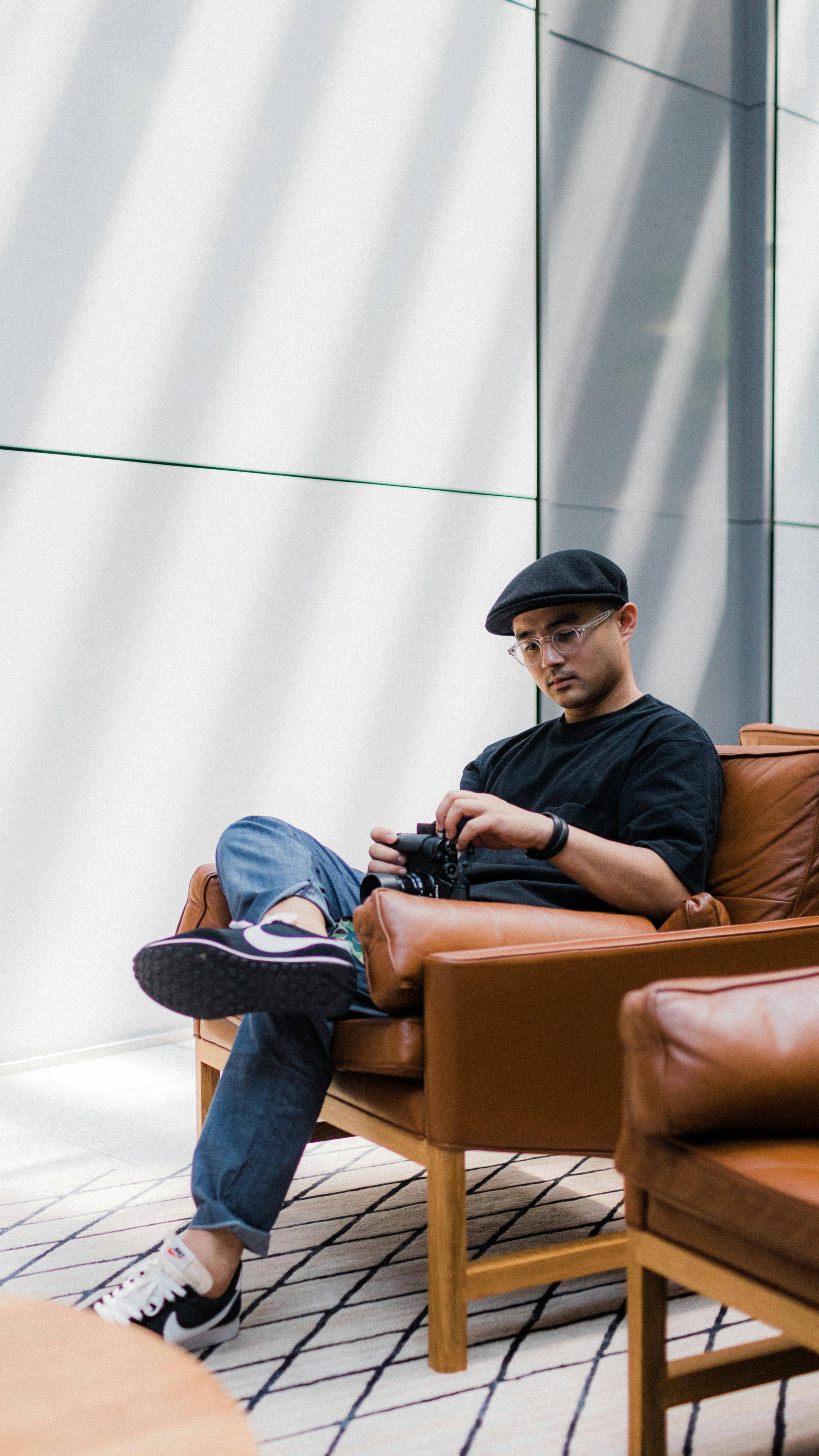 在现代房间里，年轻人漫不经心地坐着，拿着相机，神情沉思