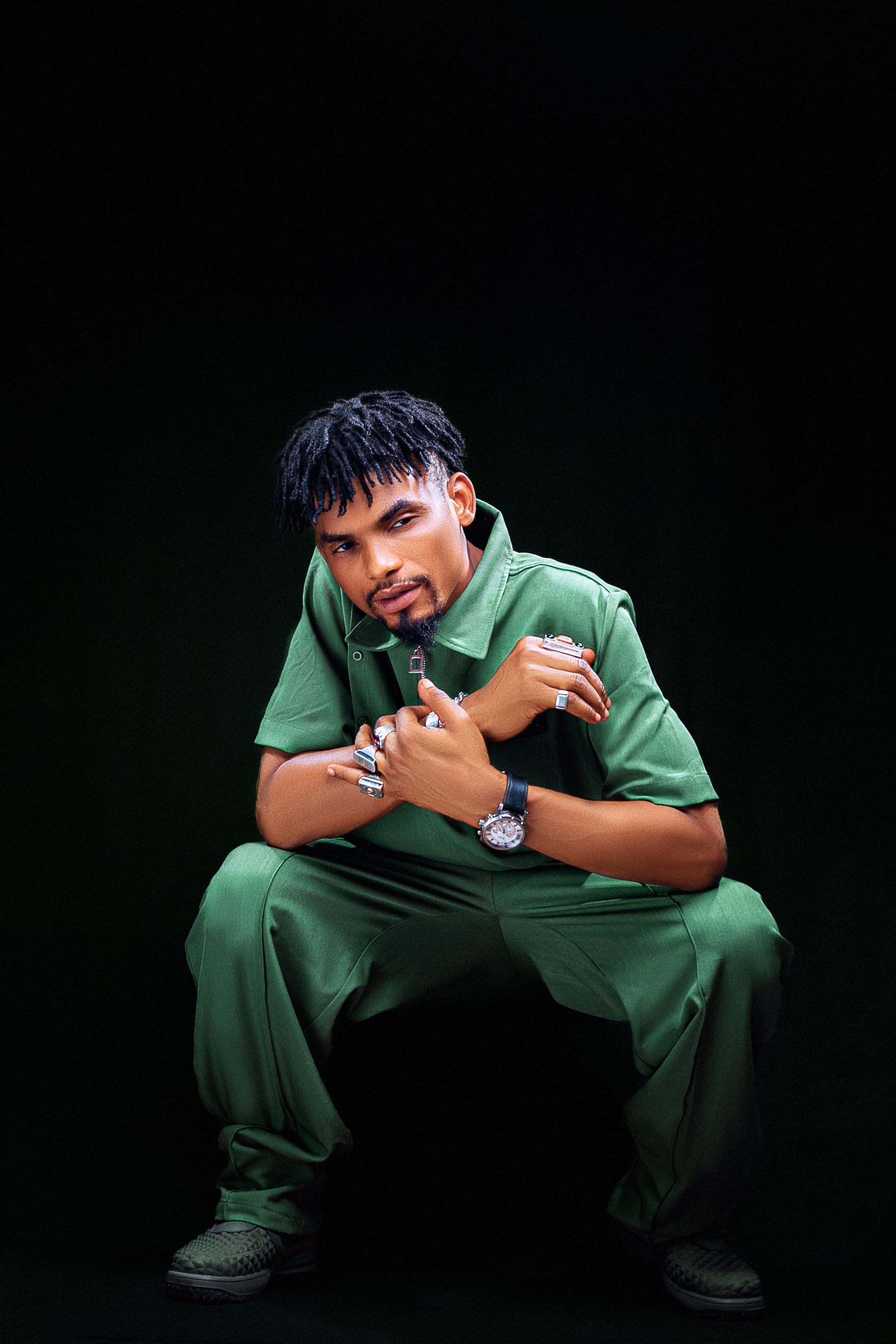 Studio portrait of a young man with an afro hairstyle wearing green clothing, showcasing vibrant style and confidence.