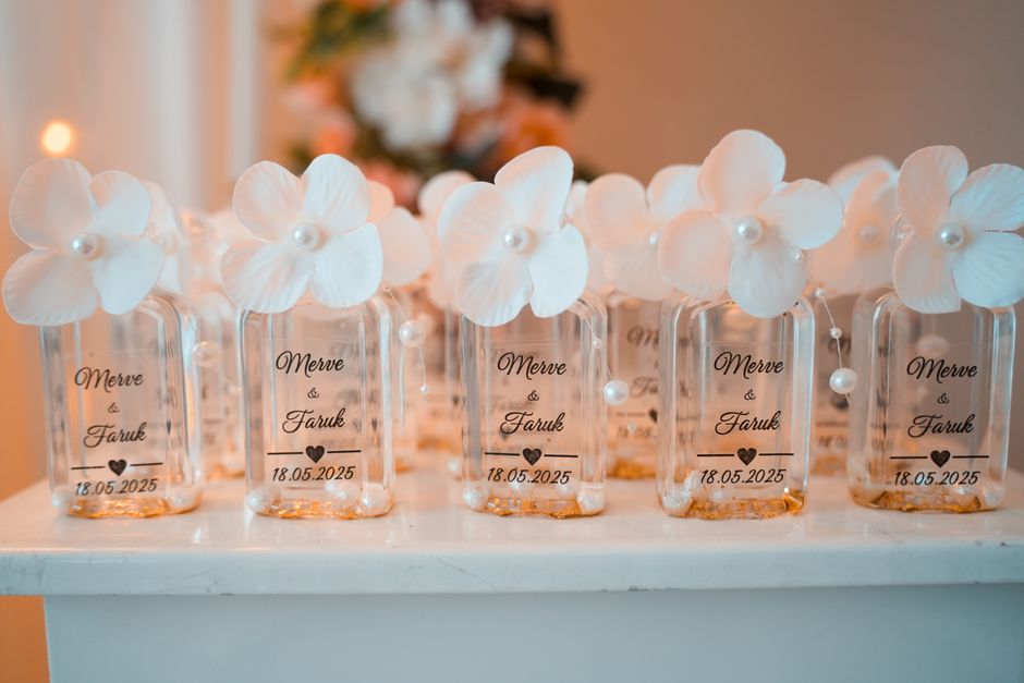 Chic wedding favor bottles with white flowers and personalized labels for Merve & Faruk's event.