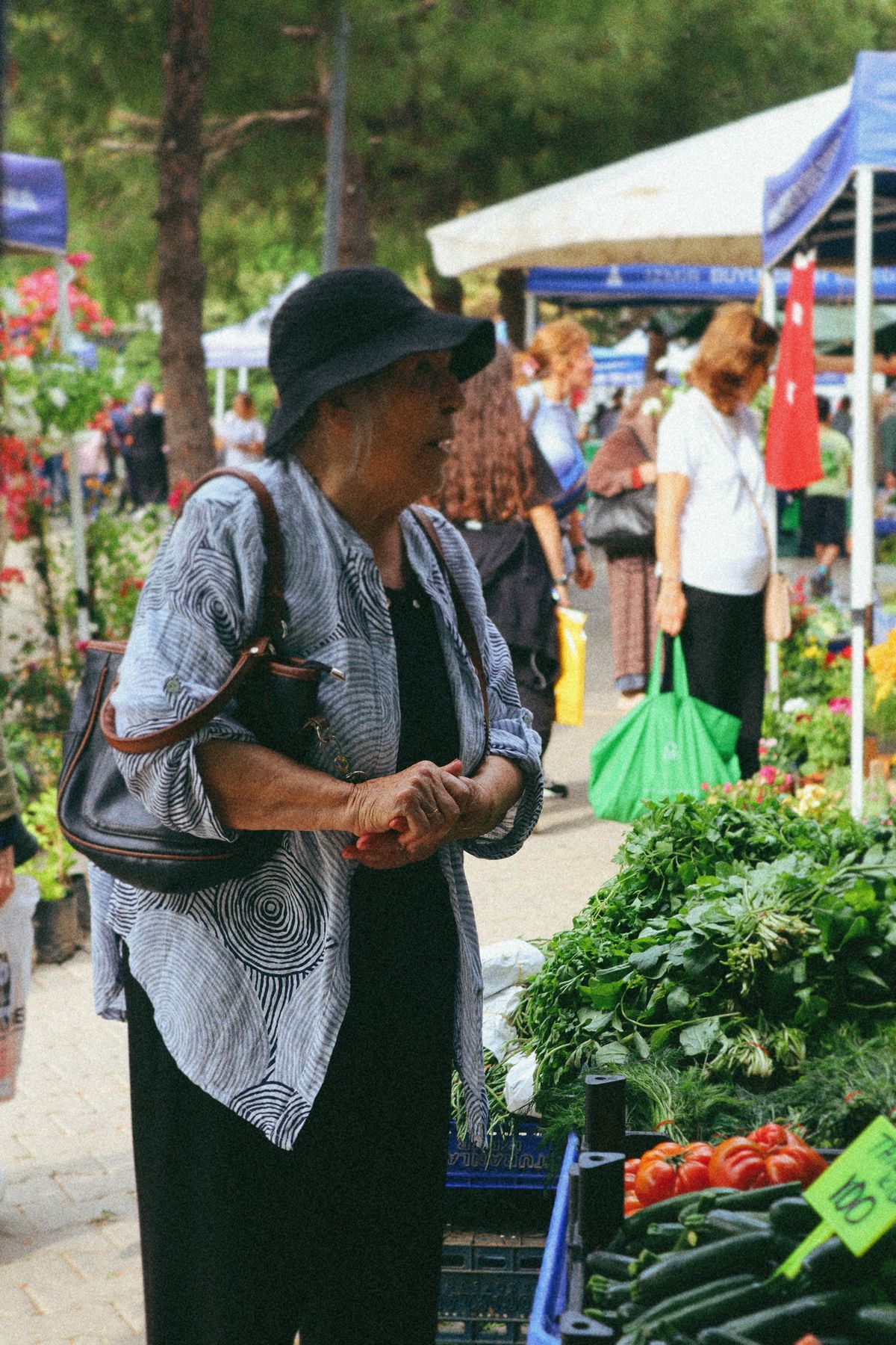 Donna anziana tra i banchi di un mercato, fotografia illustrativa