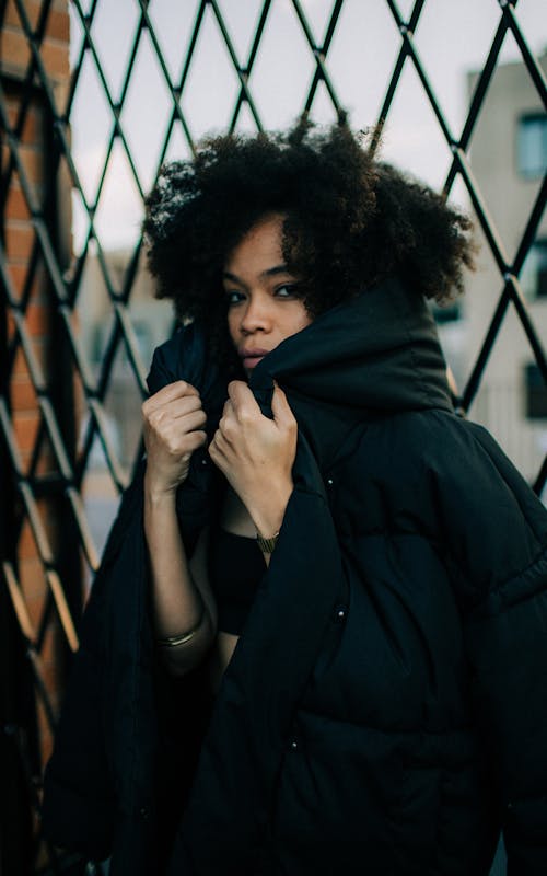 Foto Der Frau, Die Schwarze Kapuzenjacke Trägt, Die Auf Zyklonzaun Stützt