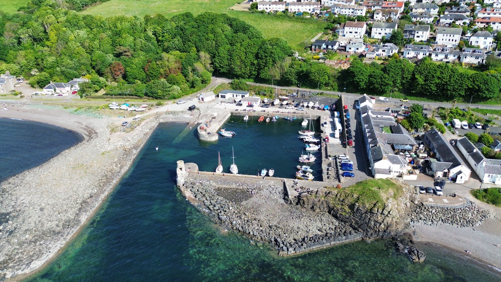 Aerial view of Dunure Harbour on the Ayrshire coast with boats and green shoreline