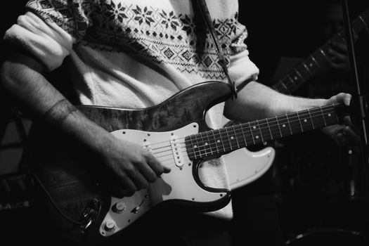 A black and white photo of a guitarist playing an electric guitar at a live music concert.