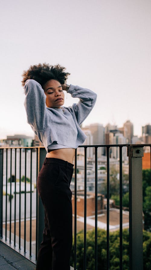 Free Woman Wearing Gray Crop Top and Black Pants Posing with Her Hands on Her Hair Stock Photo
