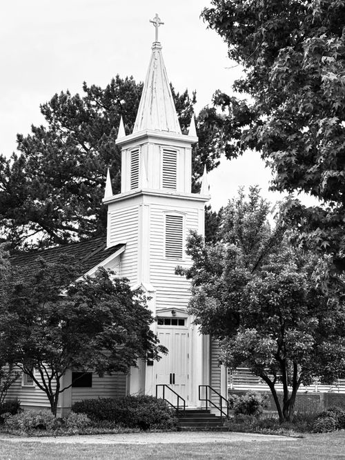 Free A picturesque white church nestled among lush trees on a sunny day in Boise, Idaho. Stock Photo