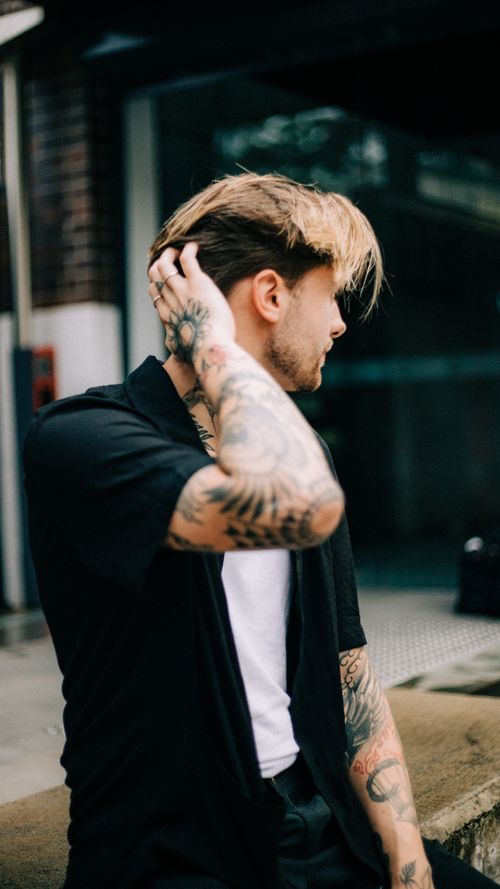 Free Portrait of a tattooed man looking away outdoors, showcasing modern urban fashion and personal style. Stock Photo