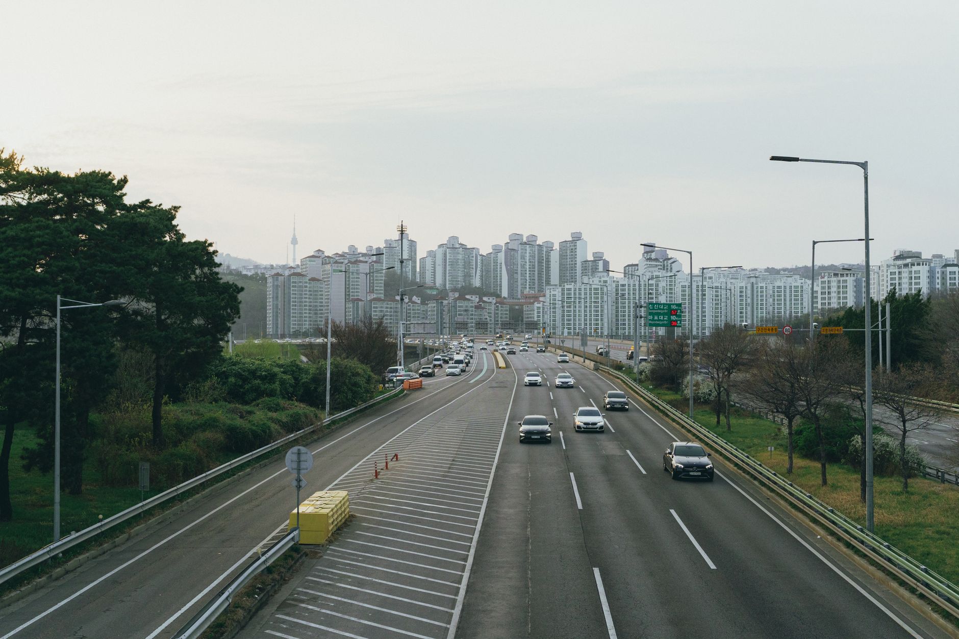 Highway view leading into Seoul with high-rise buildings and Namsan Tower in the background during spring.