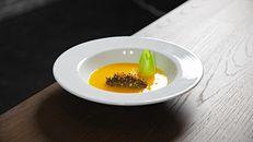 Elegant dessert featuring mango puree with unique garnish on a white plate.