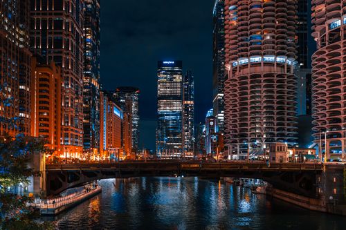 Free A captivating night view of the Chicago River flanked by towering skyscrapers and illuminated city lights. Stock Photo